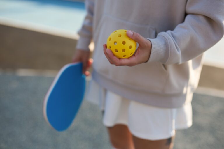 Imagen que muestra el equipamiento básico de pickleball: una pala sólida, una pelota perforada de plástico